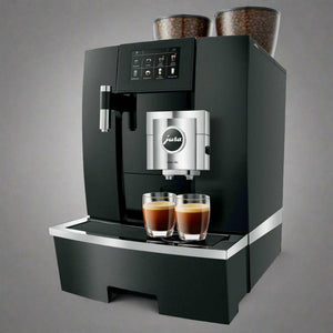 Cafetera automática Jura GIGA X8c en aluminio negro con dos tazas de café servido.