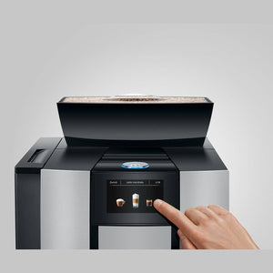 Mano interactuando con la pantalla táctil de la cafetera Jura GIGA X3 Aluminium.